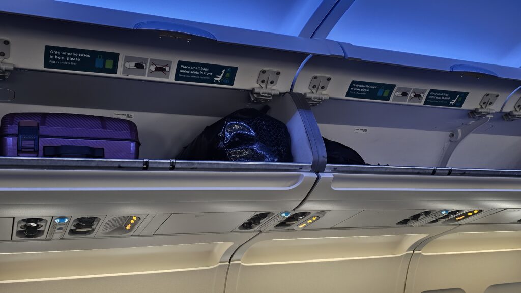 a luggage in a shelf on an airplane