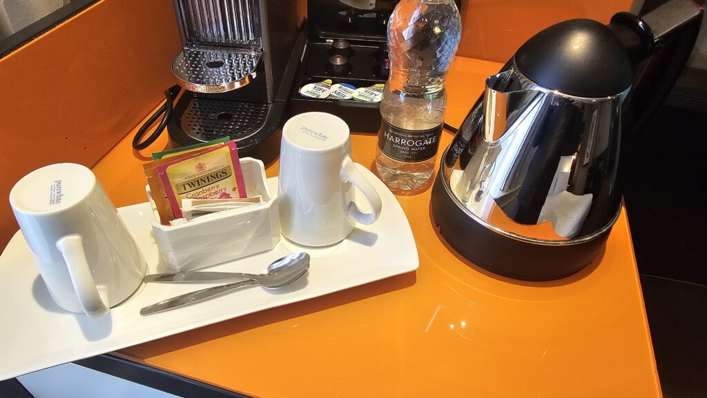 a coffee machine and a tray with a white mug and a bottle of water