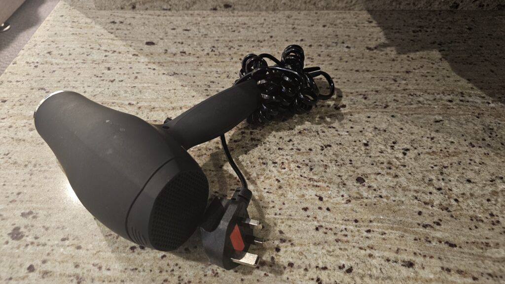 a black hair dryer with a cord