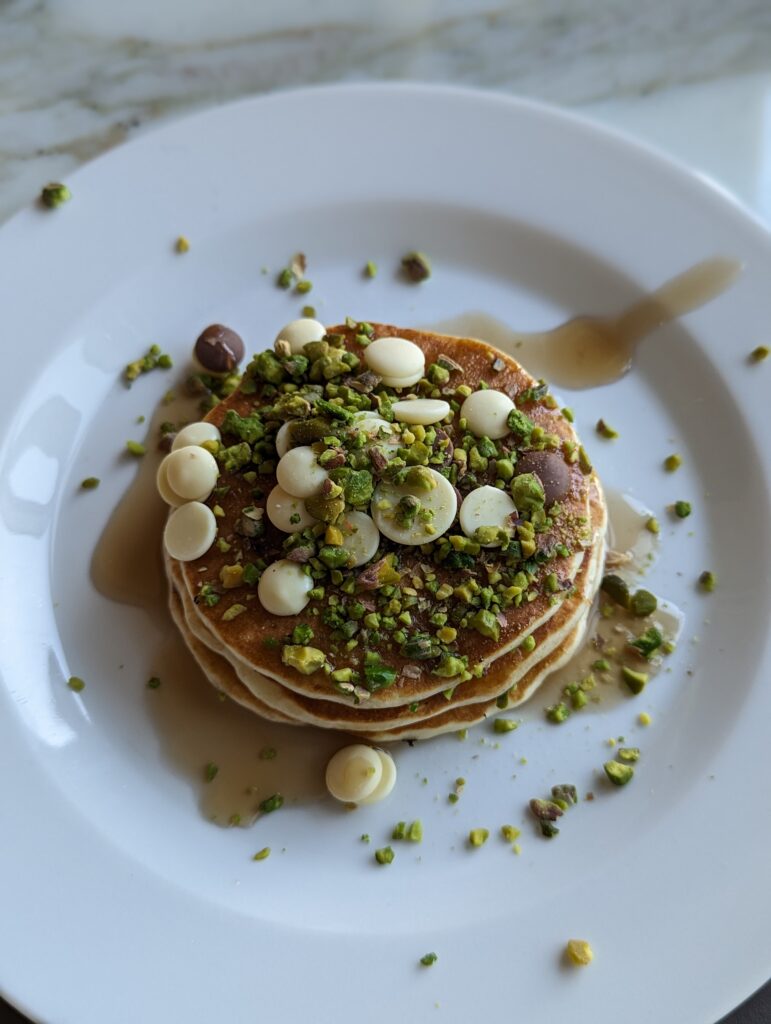 a stack of pancakes with chocolate chips and nuts on top