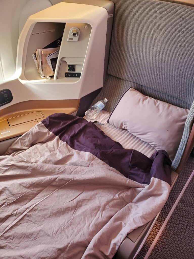 a bed with a pillow and a bottle of water in the back of a plane
