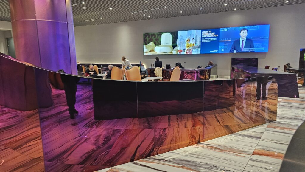 a group of people sitting at a table in a room with a large screen