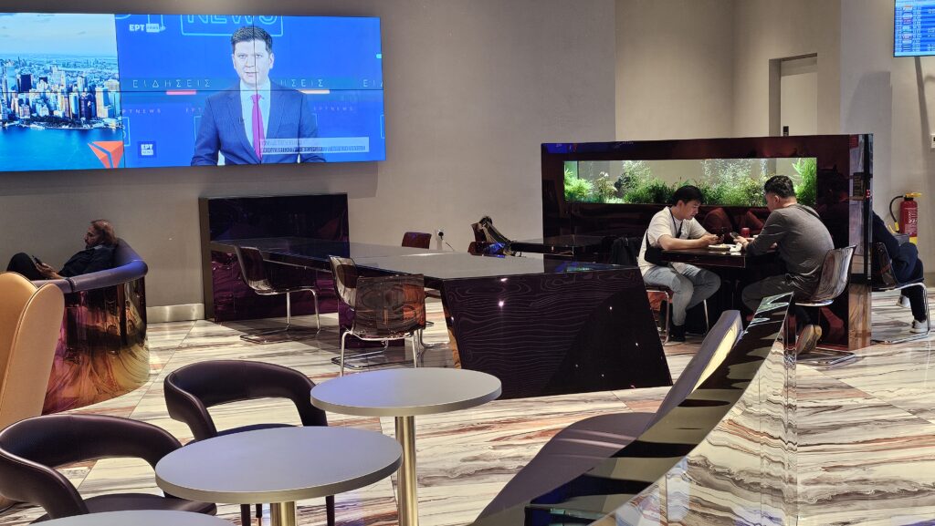 a room with a television and a man sitting at a table