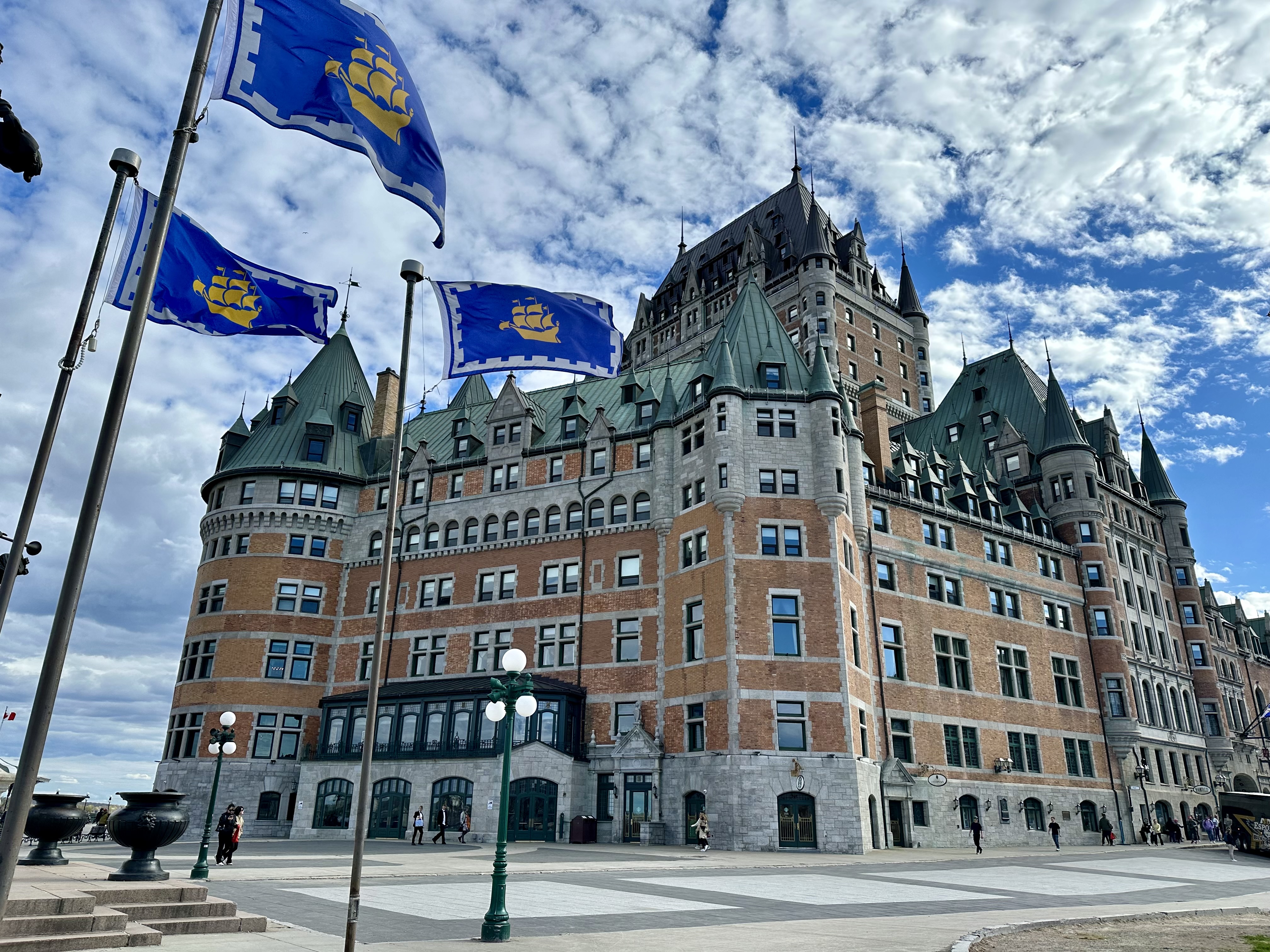 a large building with flags in front of it with Château Frontenac in the background