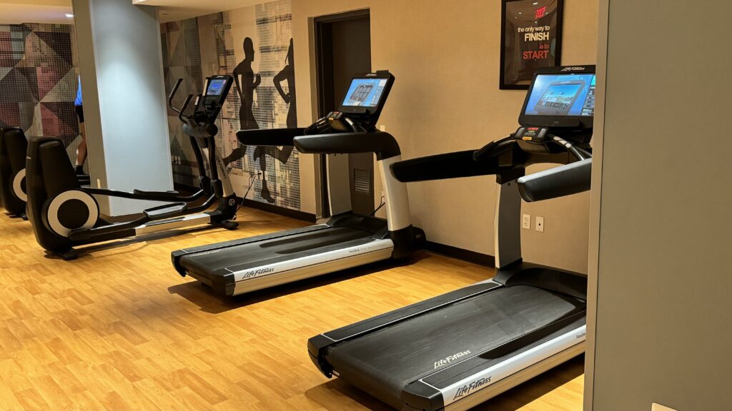 a room with treadmills and a wall with a poster on the wall