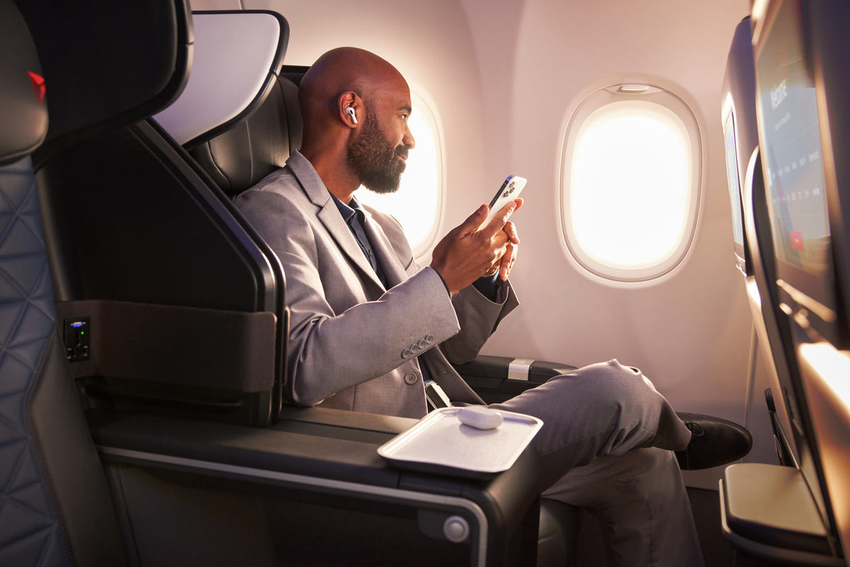 a man sitting in an airplane looking at his phone