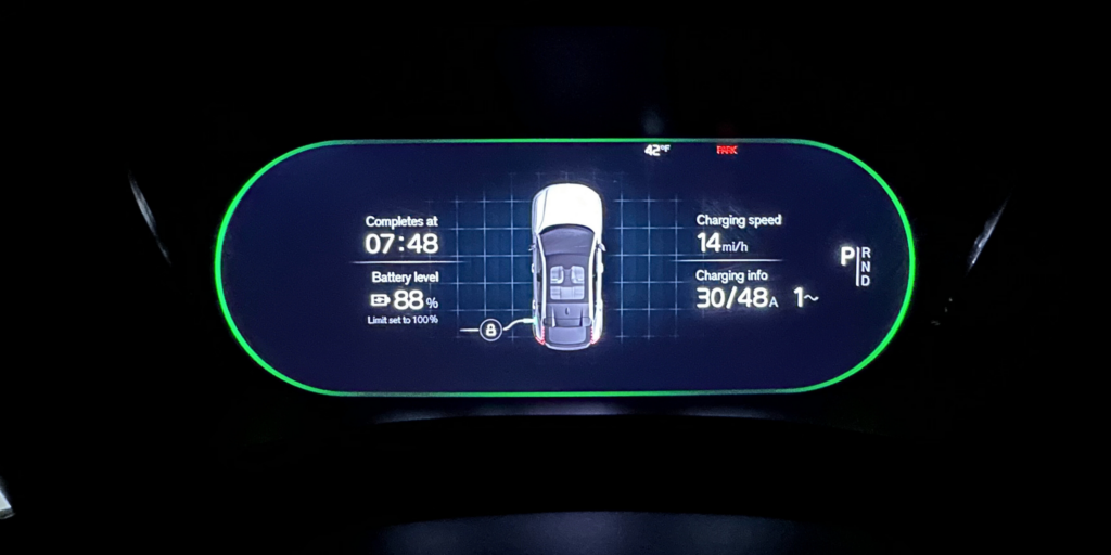 The digital gauge cluster on an electric vehicle showing charging status.