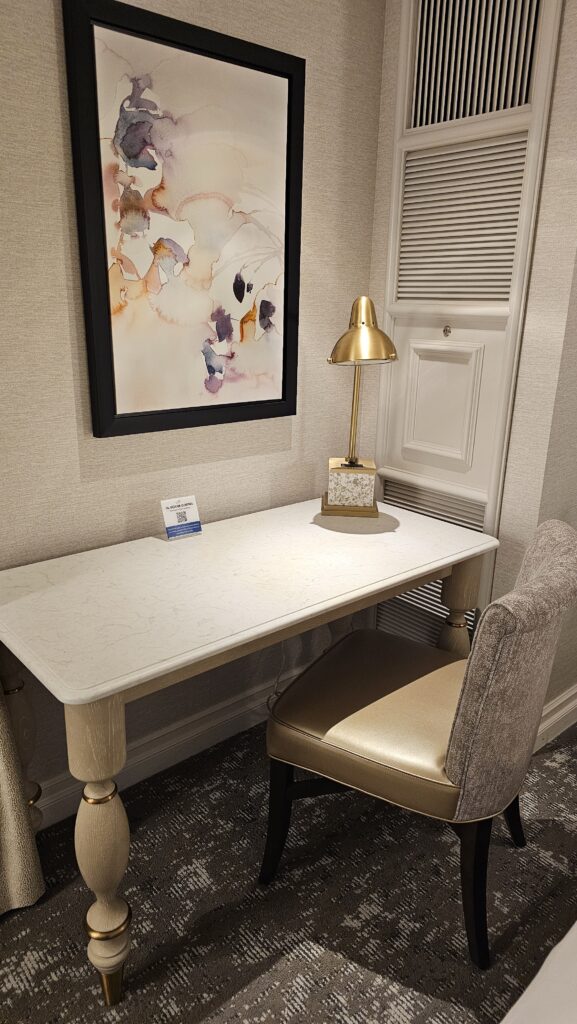 a desk with a lamp and a framed picture on the wall