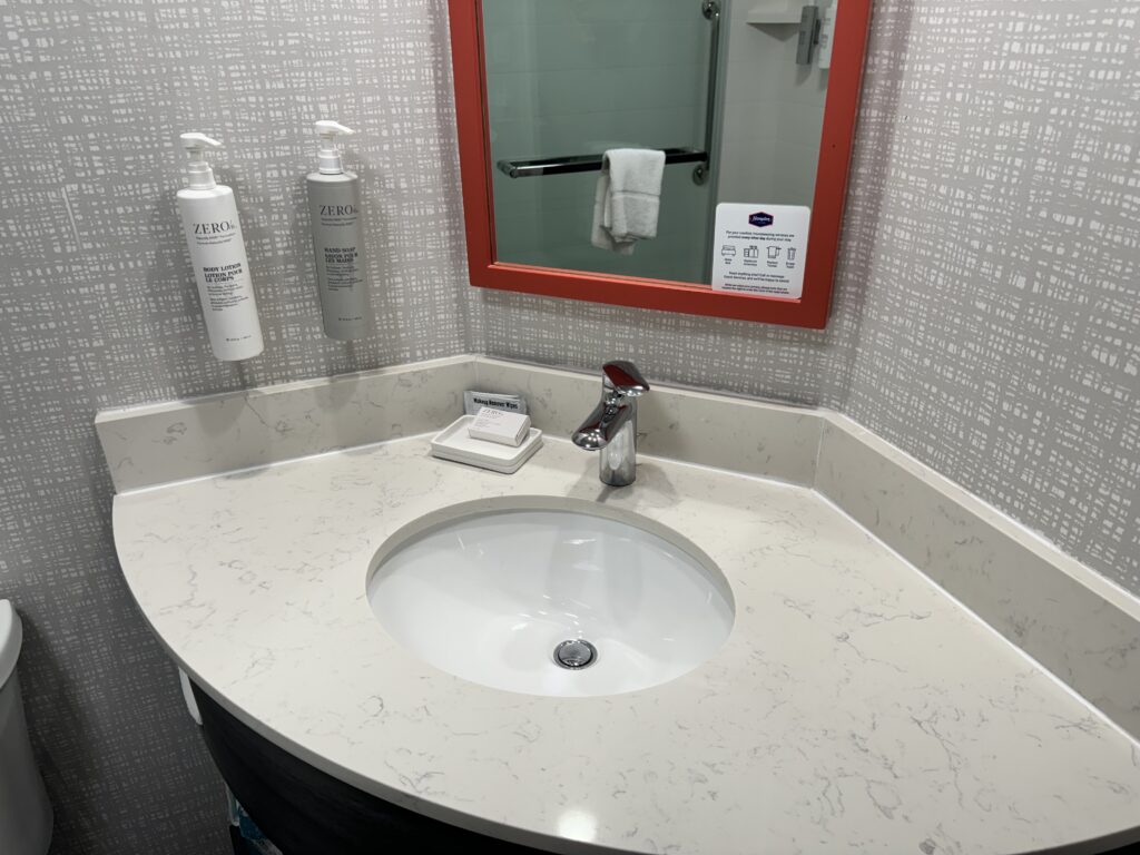 a bathroom sink with a mirror and soap dispenser