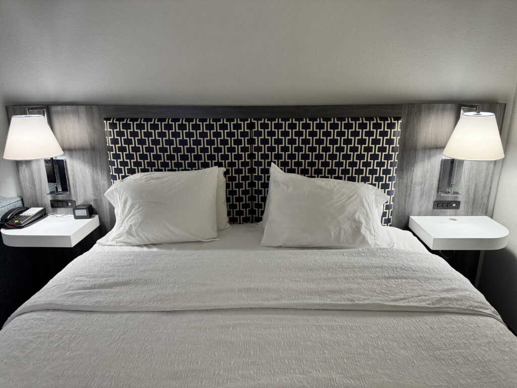 a bed with white sheets and pillows