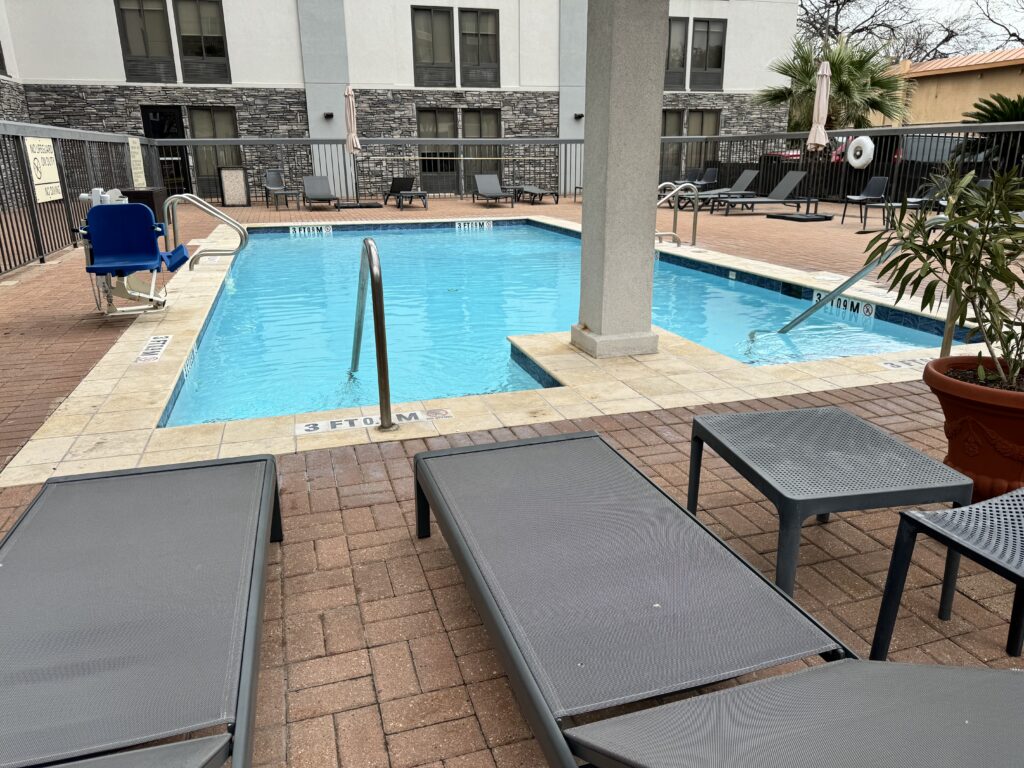 a pool with lounge chairs and a building