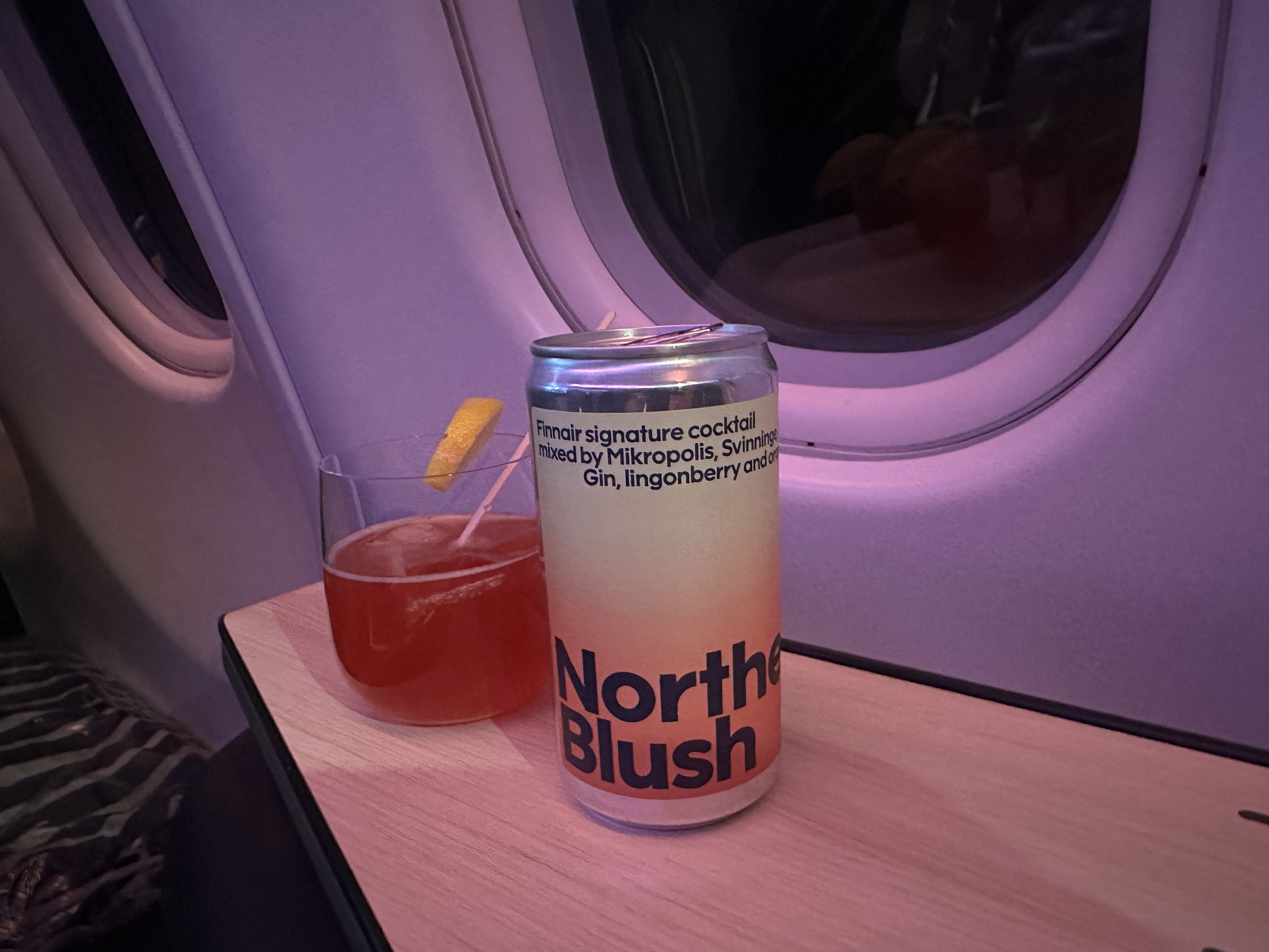 a can of beverage next to a drink on a table