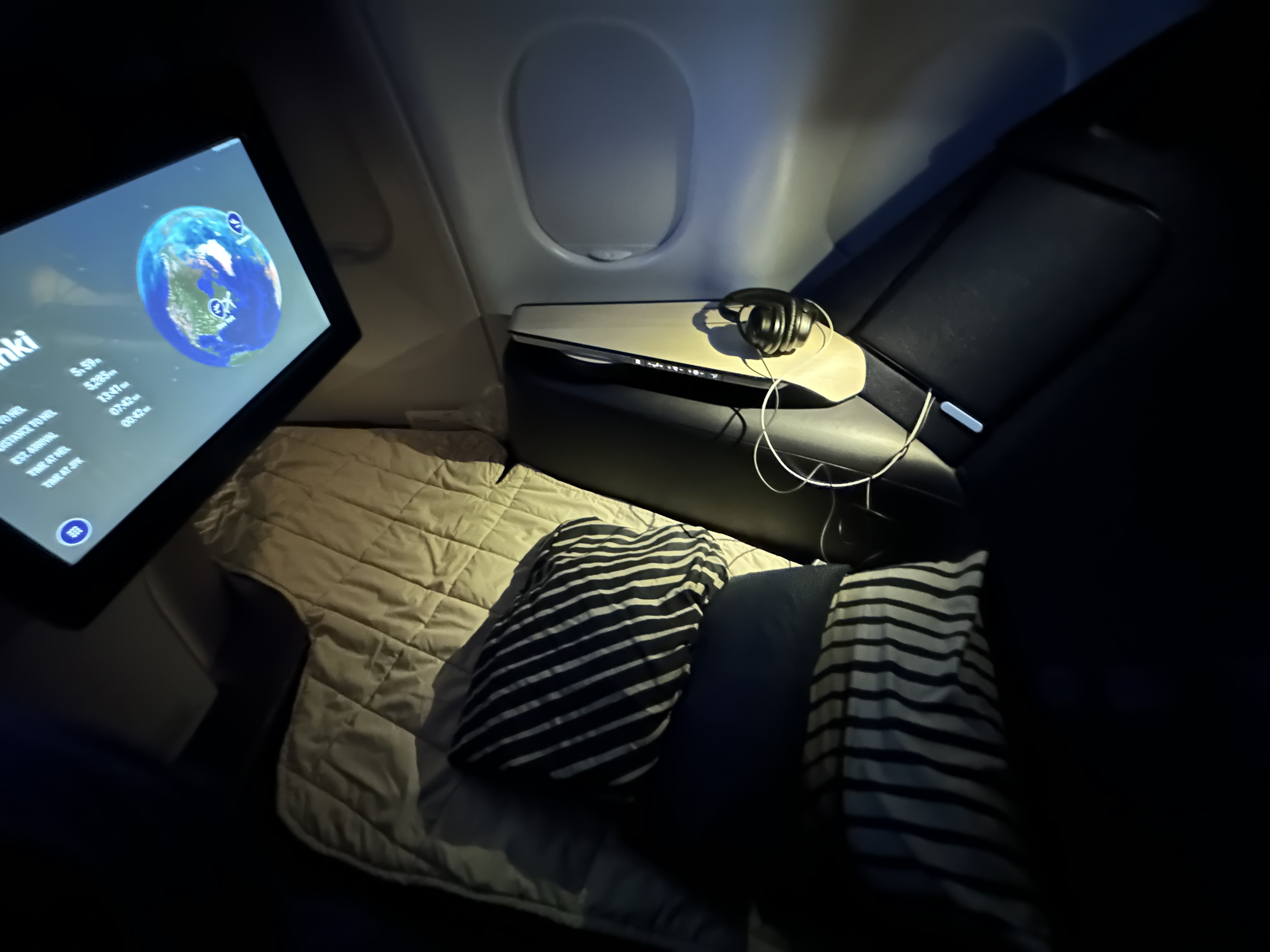 a bed with a monitor and headphones on it in Finnair A330 Business Class