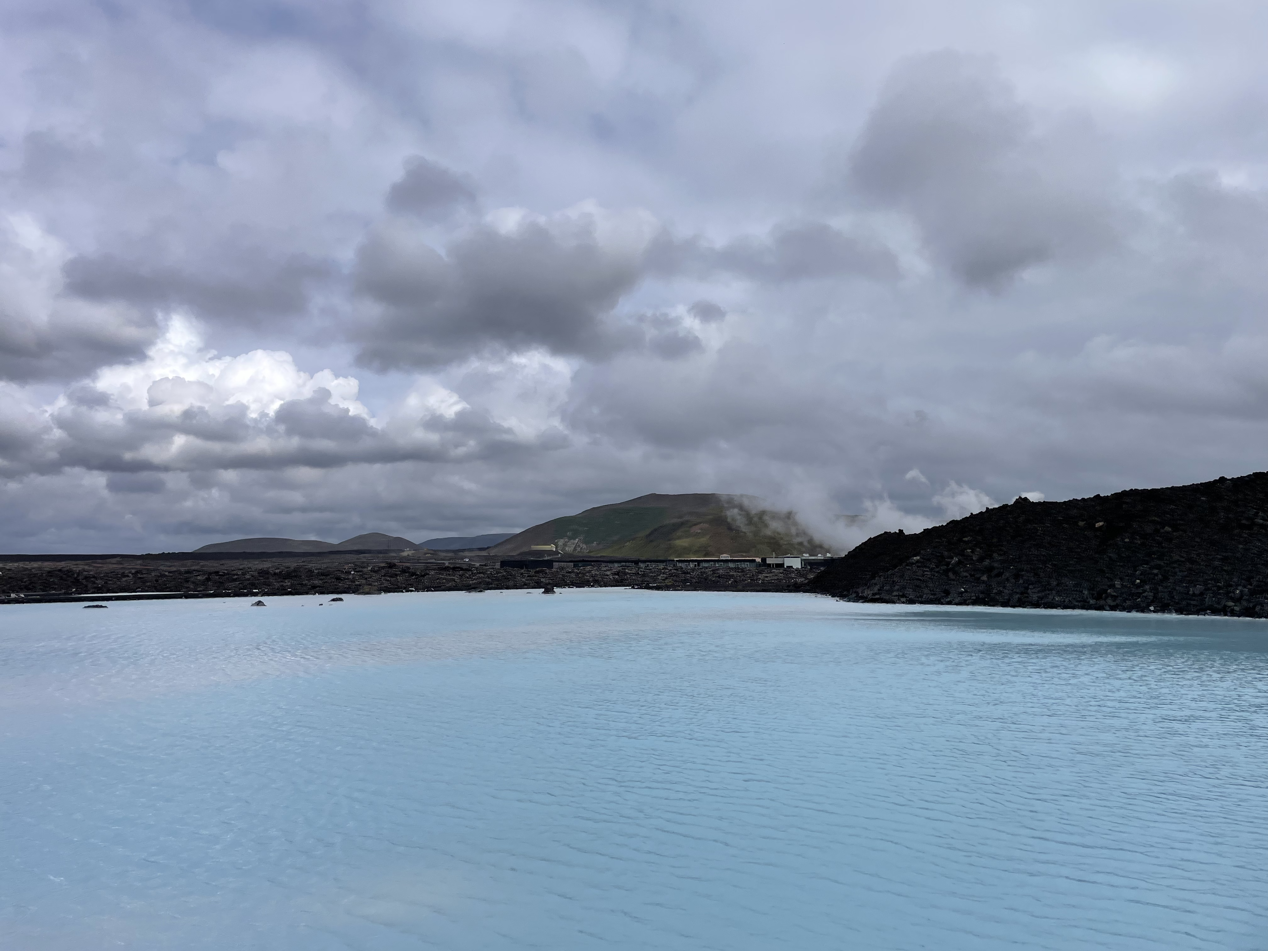 a body of water with rocks and hills in the background