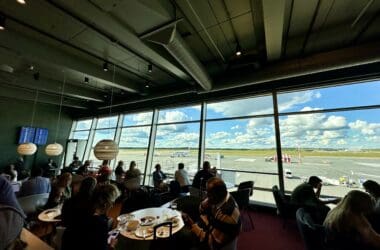 a group of people sitting at tables in a room with large windows at the Aspire Lounge Helsinki.