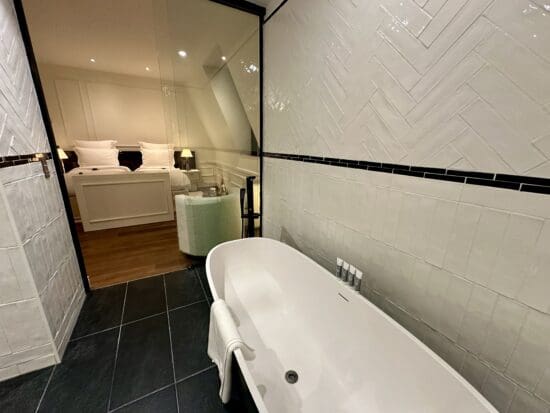 a bathroom with a tub and a bed at the Maison Delano Paris