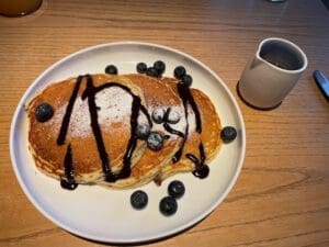 a plate of pancakes with blueberries and syrup