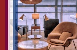 An airport lounge with upscale furniture including chairs and tables next to an assortment of colored bars that serve as decorative accents