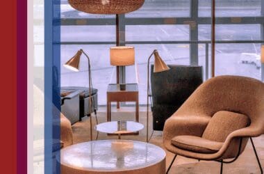 An airport lounge with upscale furniture including chairs and tables next to an assortment of colored bars that serve as decorative accents