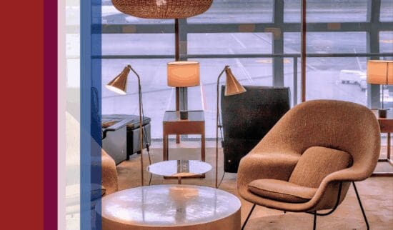 An airport lounge with upscale furniture including chairs and tables next to an assortment of colored bars that serve as decorative accents