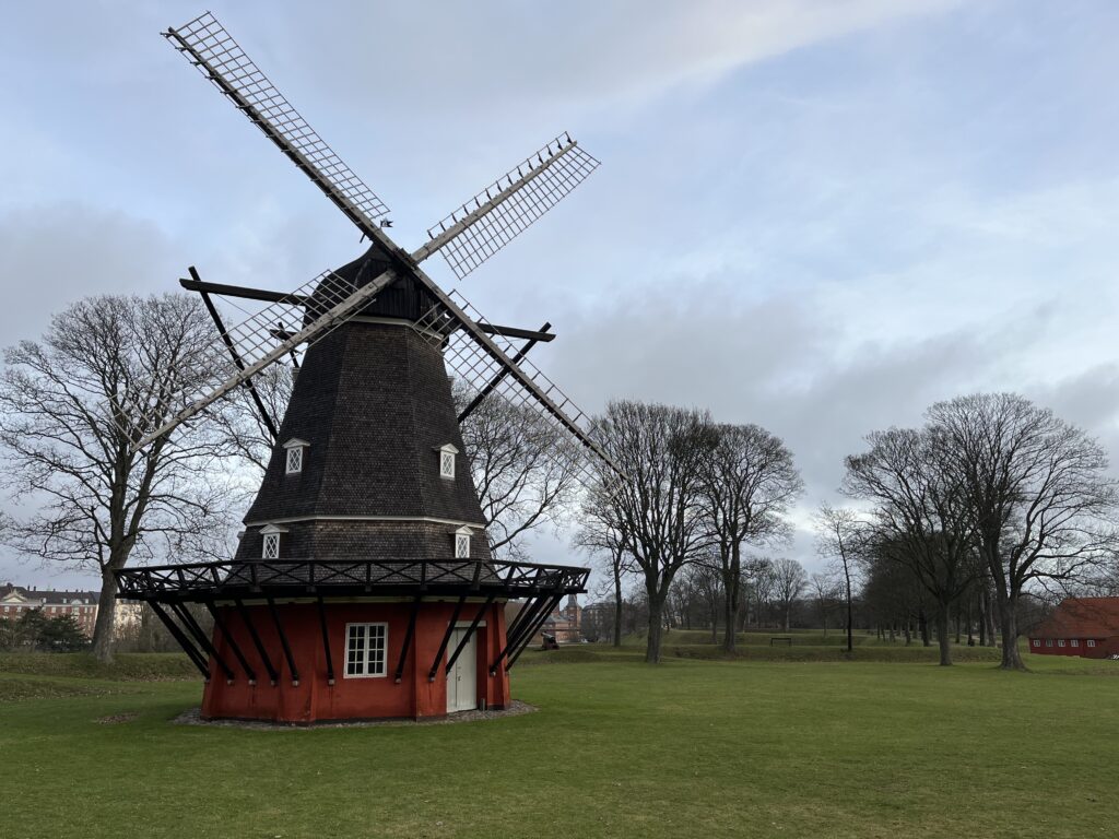 a windmill in a field with Eastham Windmill in the background