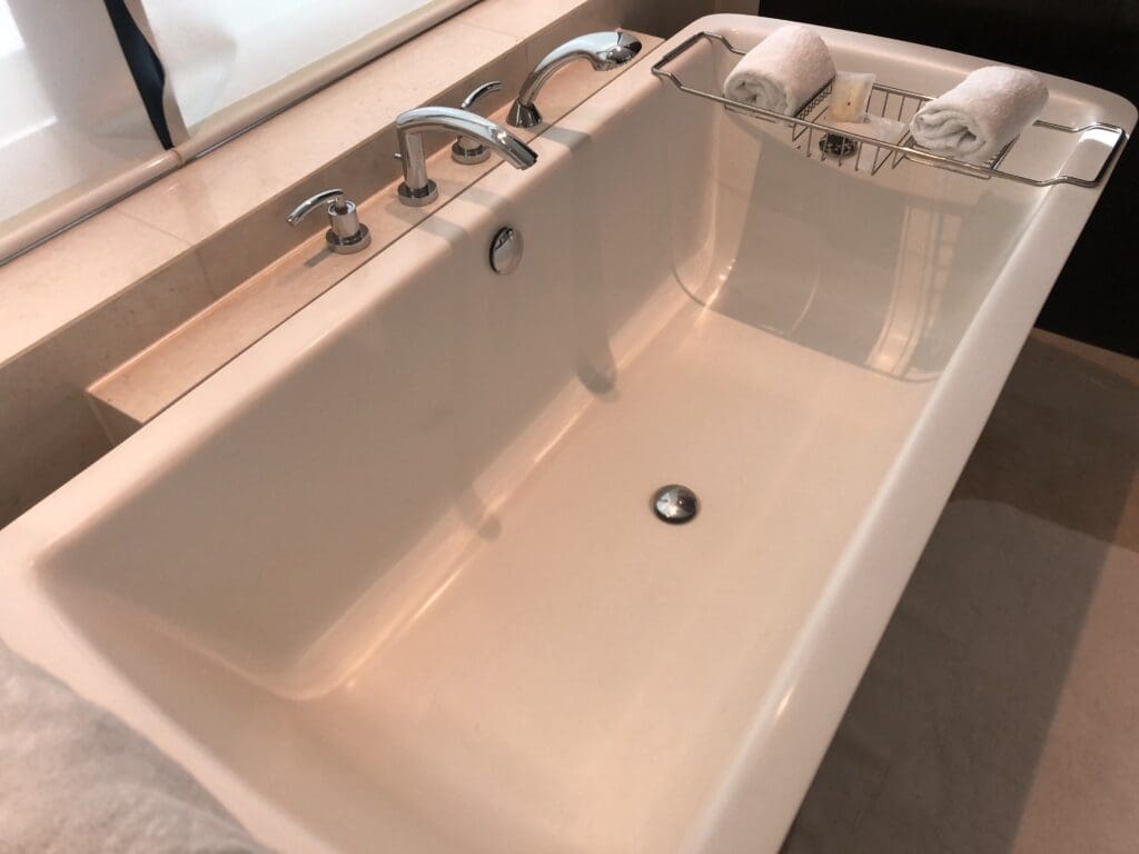 a white bathtub with silver faucets and a towel rack