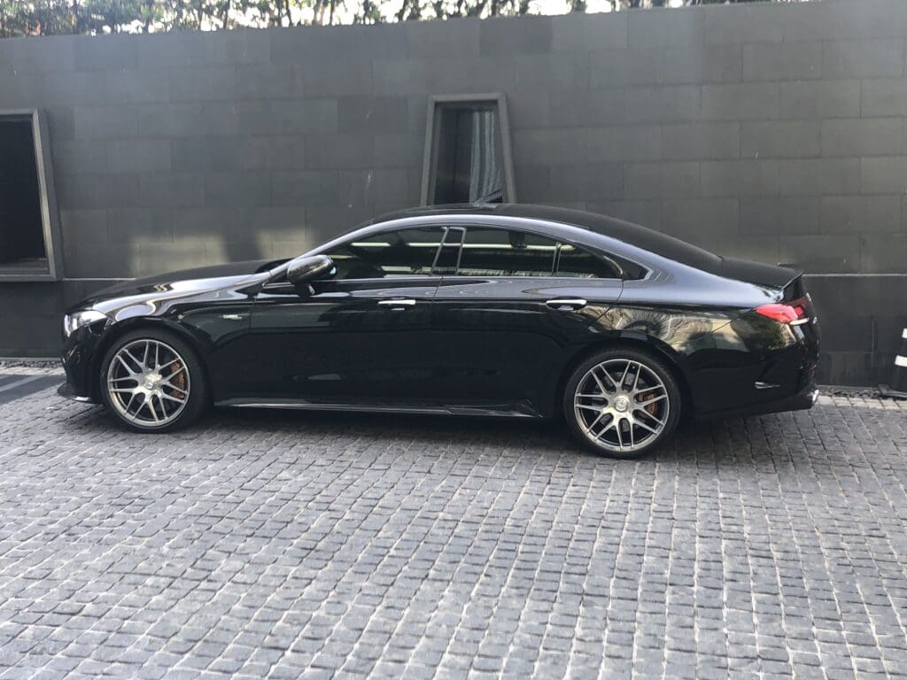 a black car parked in front of a grey wall