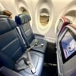 seats in a Delta Airlines A220 with a screen and a monitor