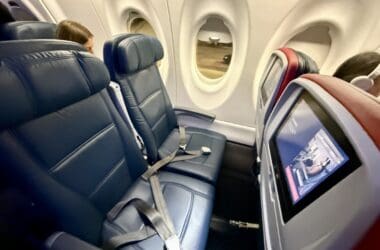 seats in a Delta Airlines A220 with a screen and a monitor