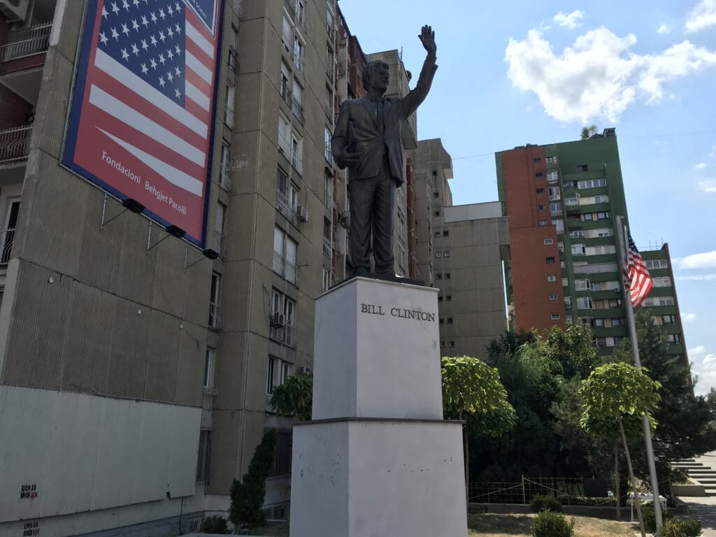 a statue of a man with his hand up in front of a building