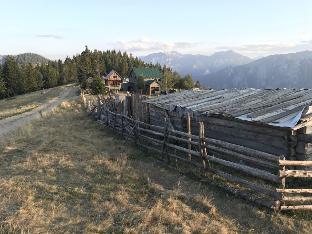 a fenced in area with houses and mountains in the background