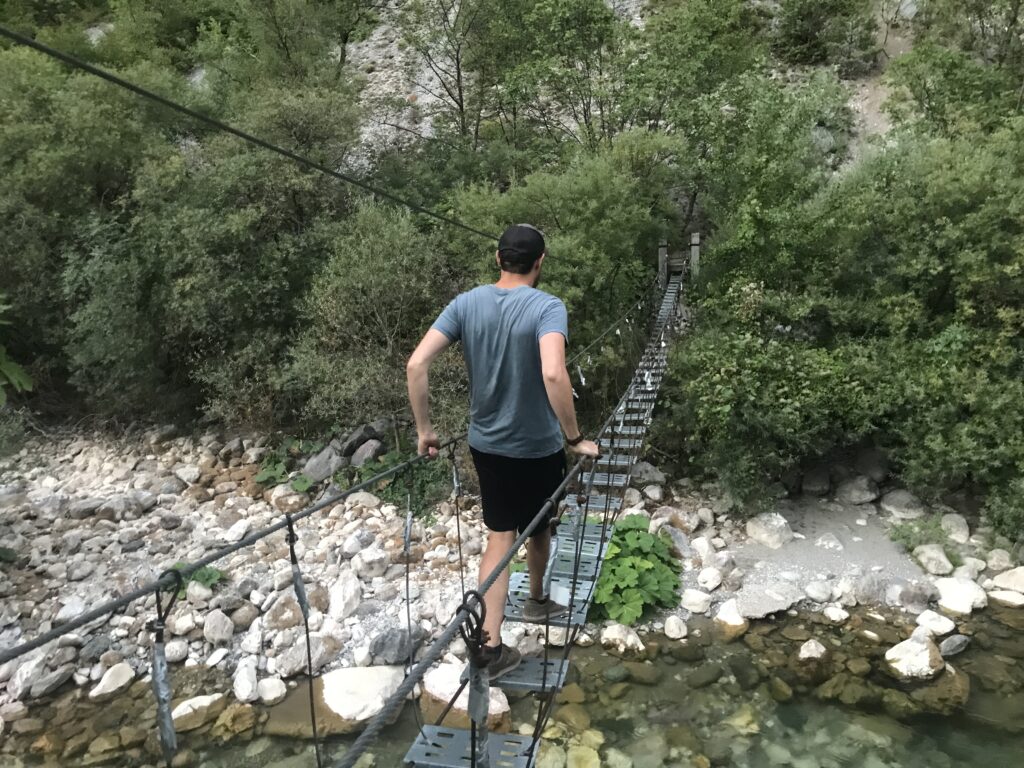 a man walking on a suspension bridge over a river