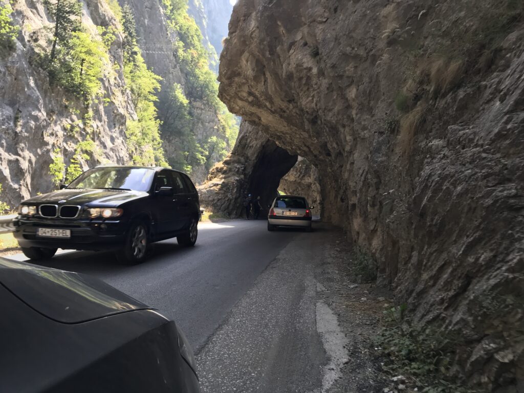 cars on a road with a cave in the background