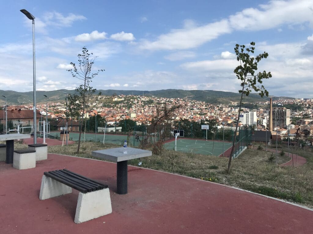 a park with benches and a city in the background