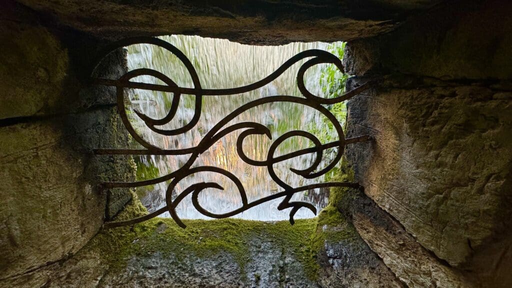 a metal gate with a waterfall in the background