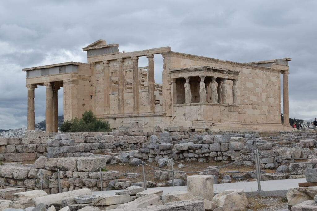 a stone building with columns and pillars with Erechtheion in the background