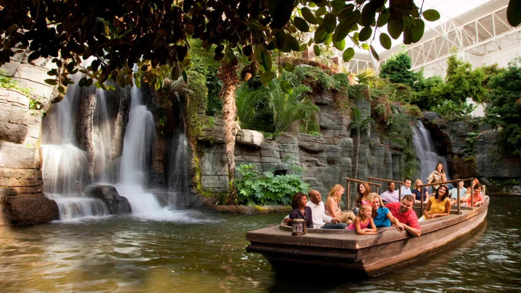 a group of people on a boat in a pond with a waterfall