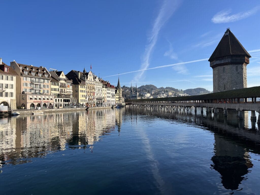 a bridge over water with buildings and a round tower