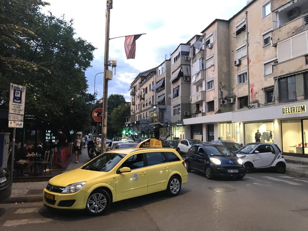 a yellow car on a street with cars parked in front of buildings