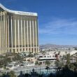 a large building with a pool and palm trees with Mandalay Bay in the background