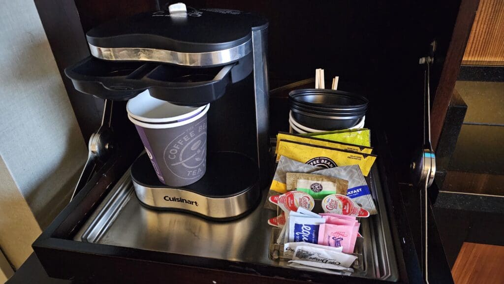 a coffee maker with a container of coffee and condiments