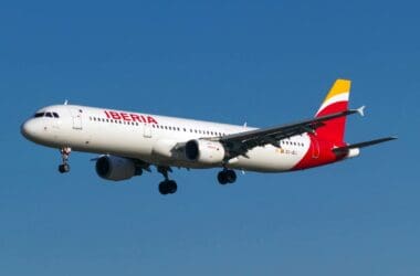 a white airplane with red and yellow wings flying in the sky