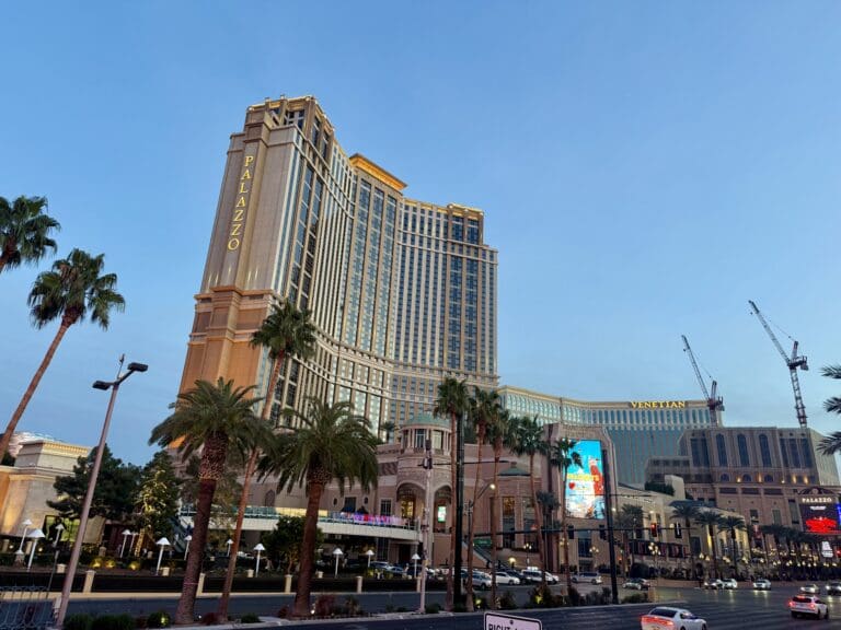 a large building with palm trees and a street