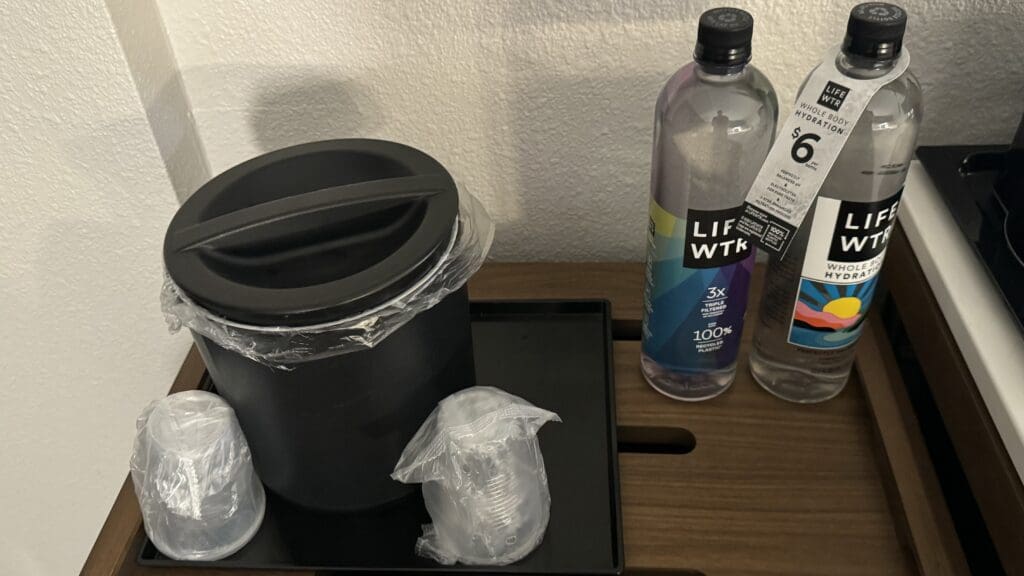 a black container with plastic wrap around it and plastic cups on a black tray