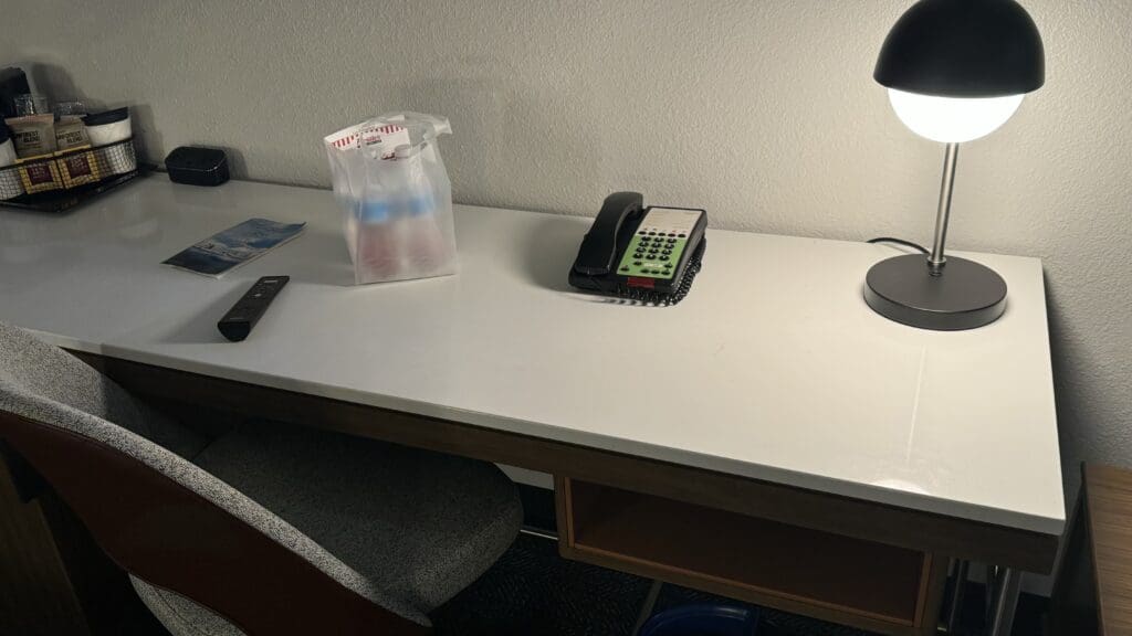 a desk with a phone and a lamp