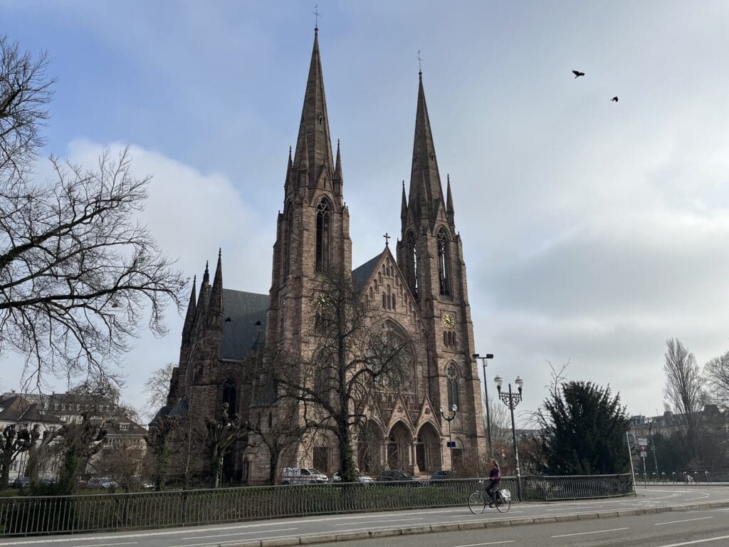 a building with tall spires and a street and trees