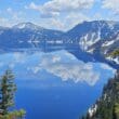 a lake with snow covered mountains and clouds in the sky