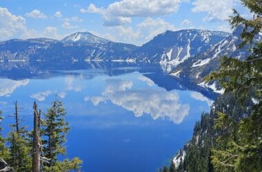 a lake with snow covered mountains and clouds in the sky