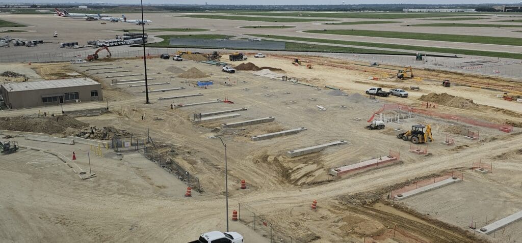 a construction site with many vehicles and a field