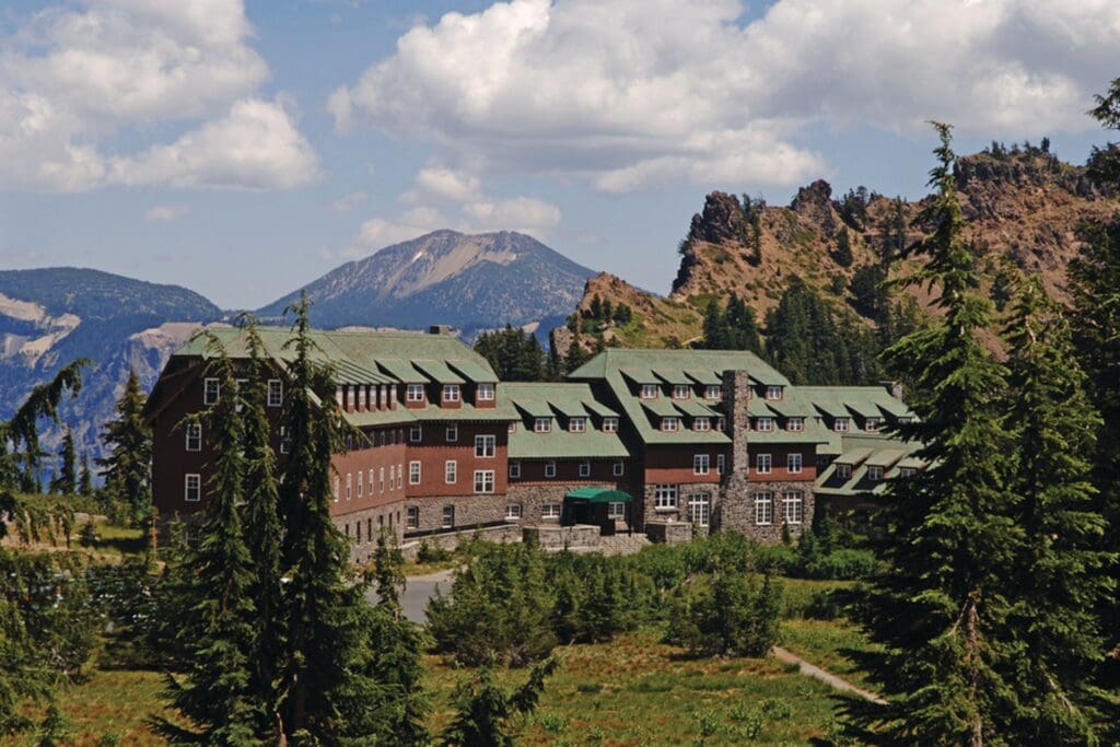 a large building with trees and mountains in the background